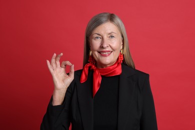 Photo of Senior woman showing okay gesture on red background