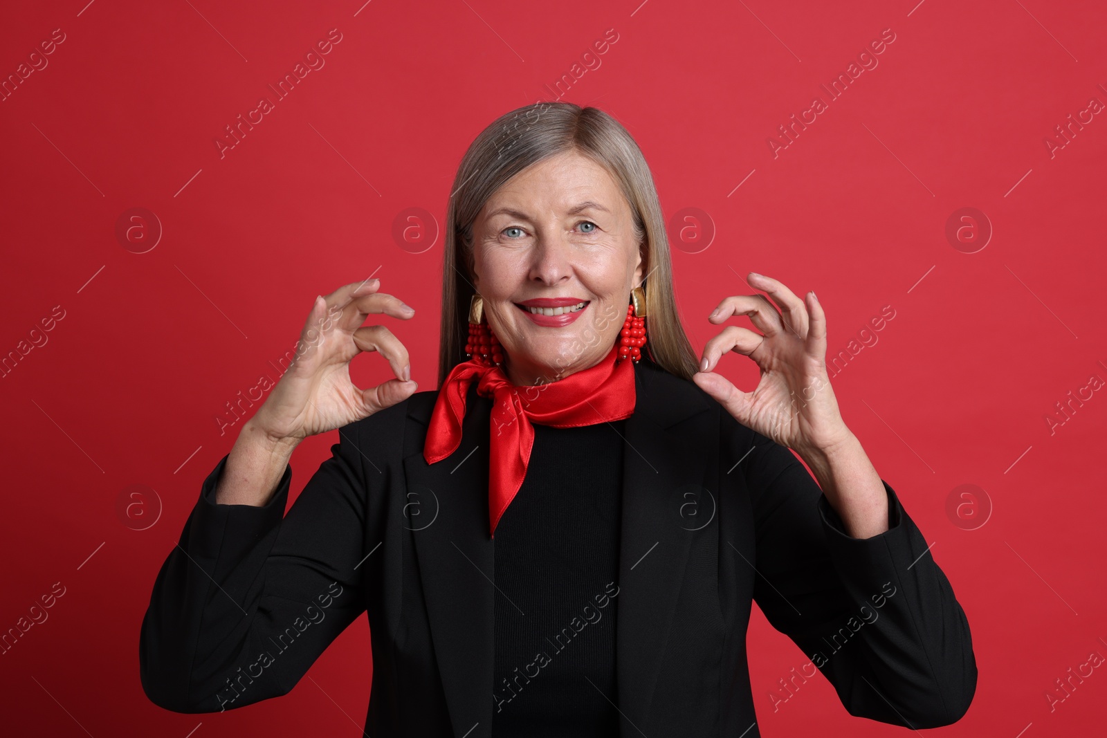 Photo of Senior woman showing okay gesture on red background