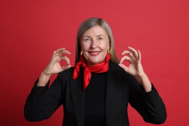 Photo of Senior woman showing okay gesture on red background