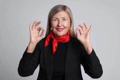 Photo of Senior woman showing okay gesture on light grey background