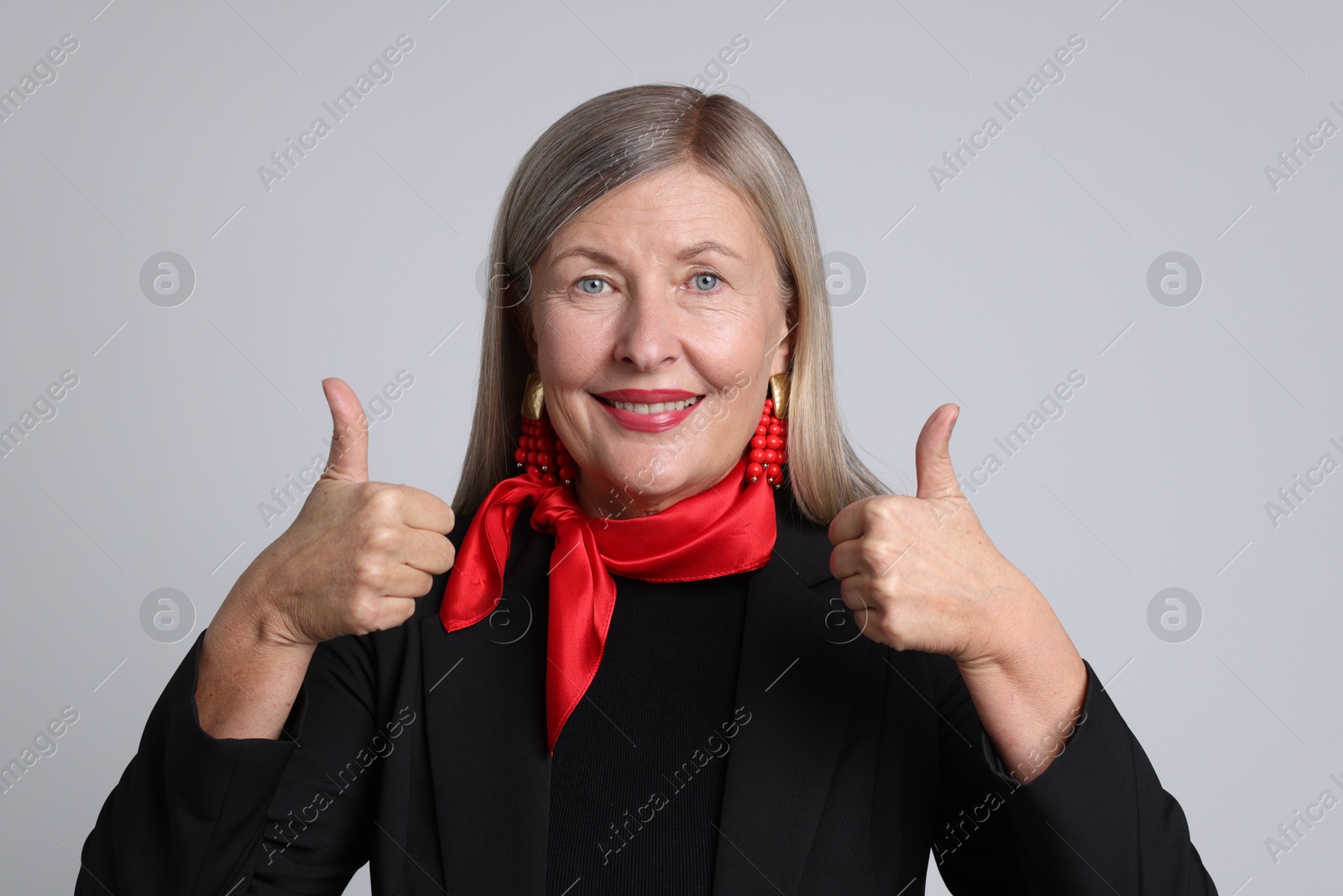 Photo of Senior woman showing thumbs up on light grey background