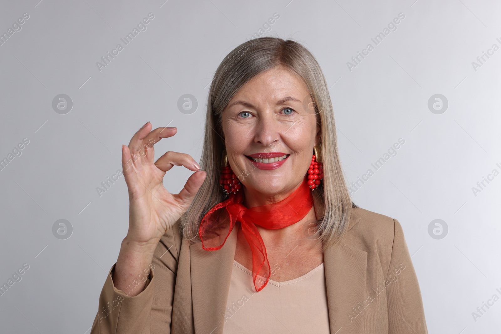 Photo of Senior woman showing okay gesture on light grey background