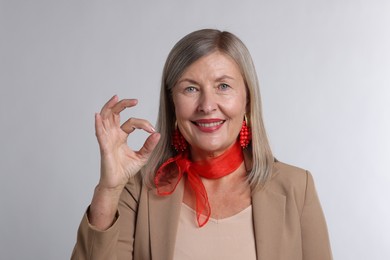 Photo of Senior woman showing okay gesture on light grey background