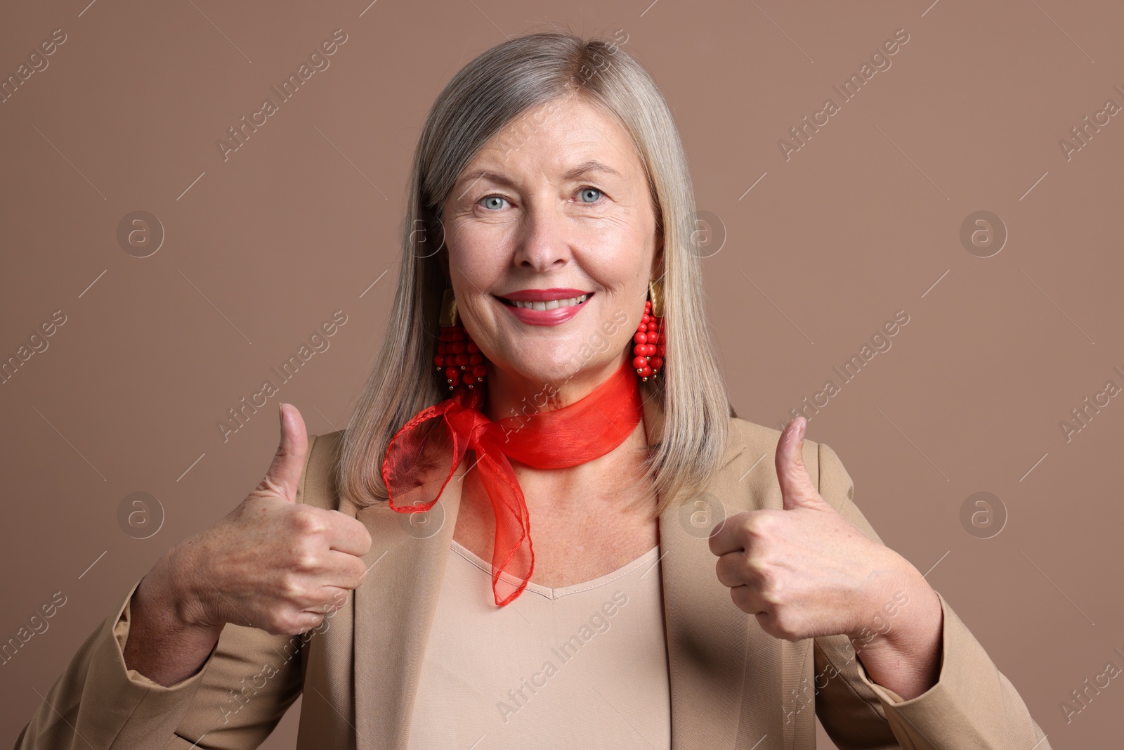 Photo of Senior woman showing thumbs up on brown background