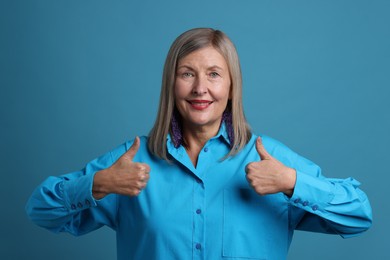 Photo of Senior woman showing thumbs up on blue background