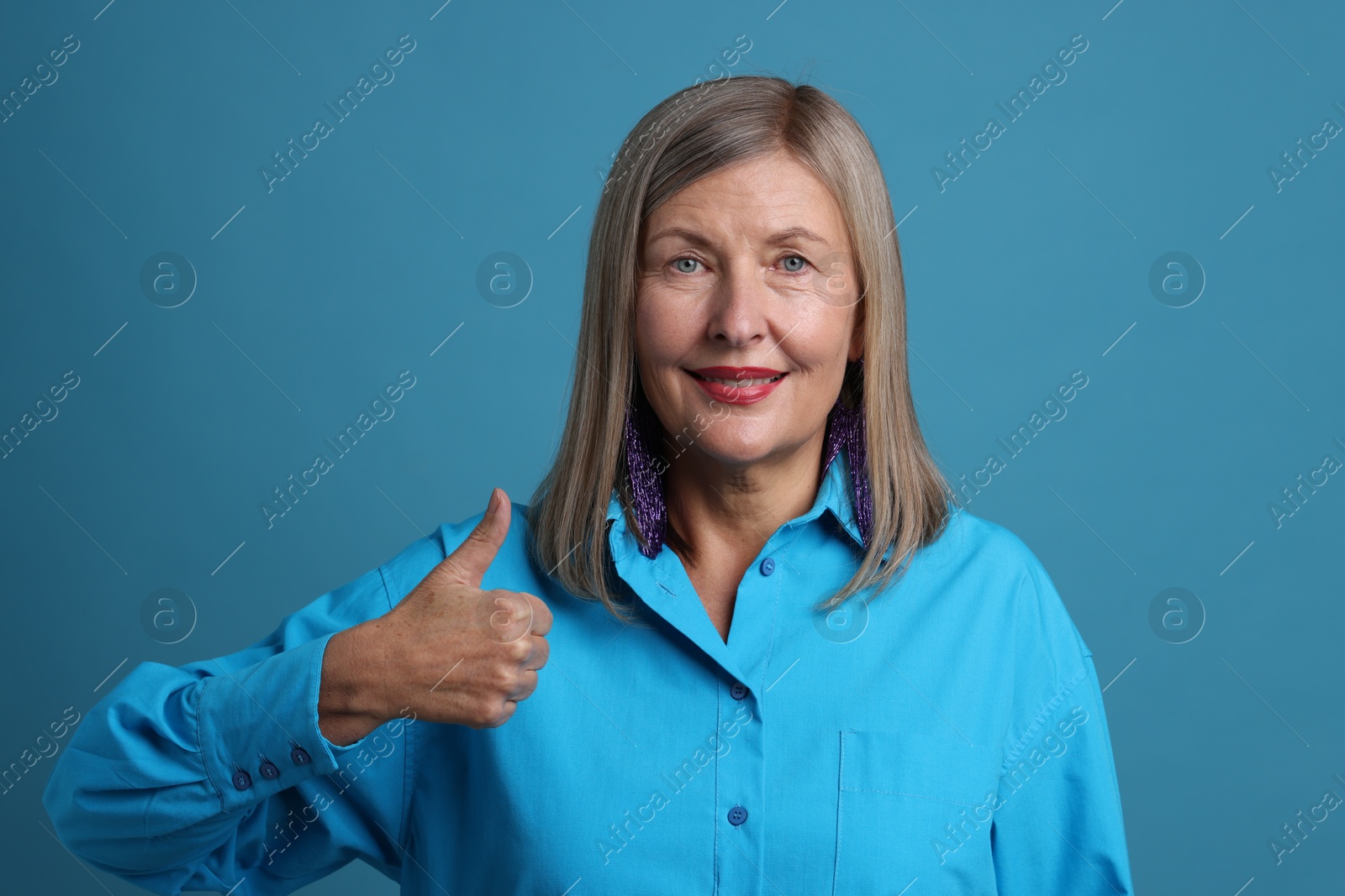 Photo of Senior woman showing thumbs up on blue background