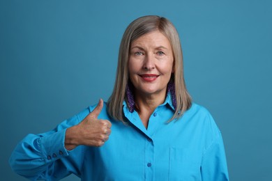 Photo of Senior woman showing thumbs up on blue background