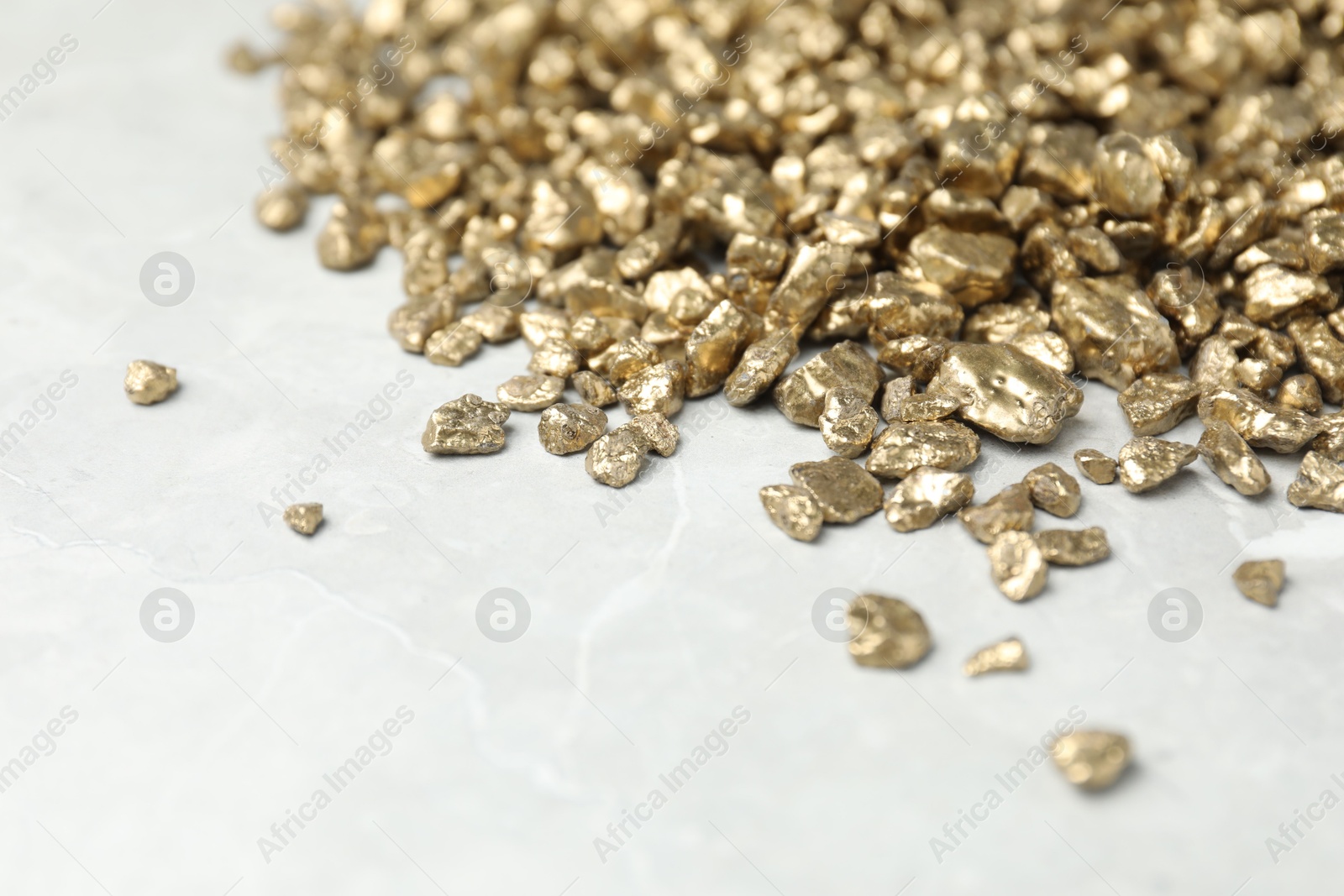 Photo of Gold nuggets on grey marble table, closeup. Space for text