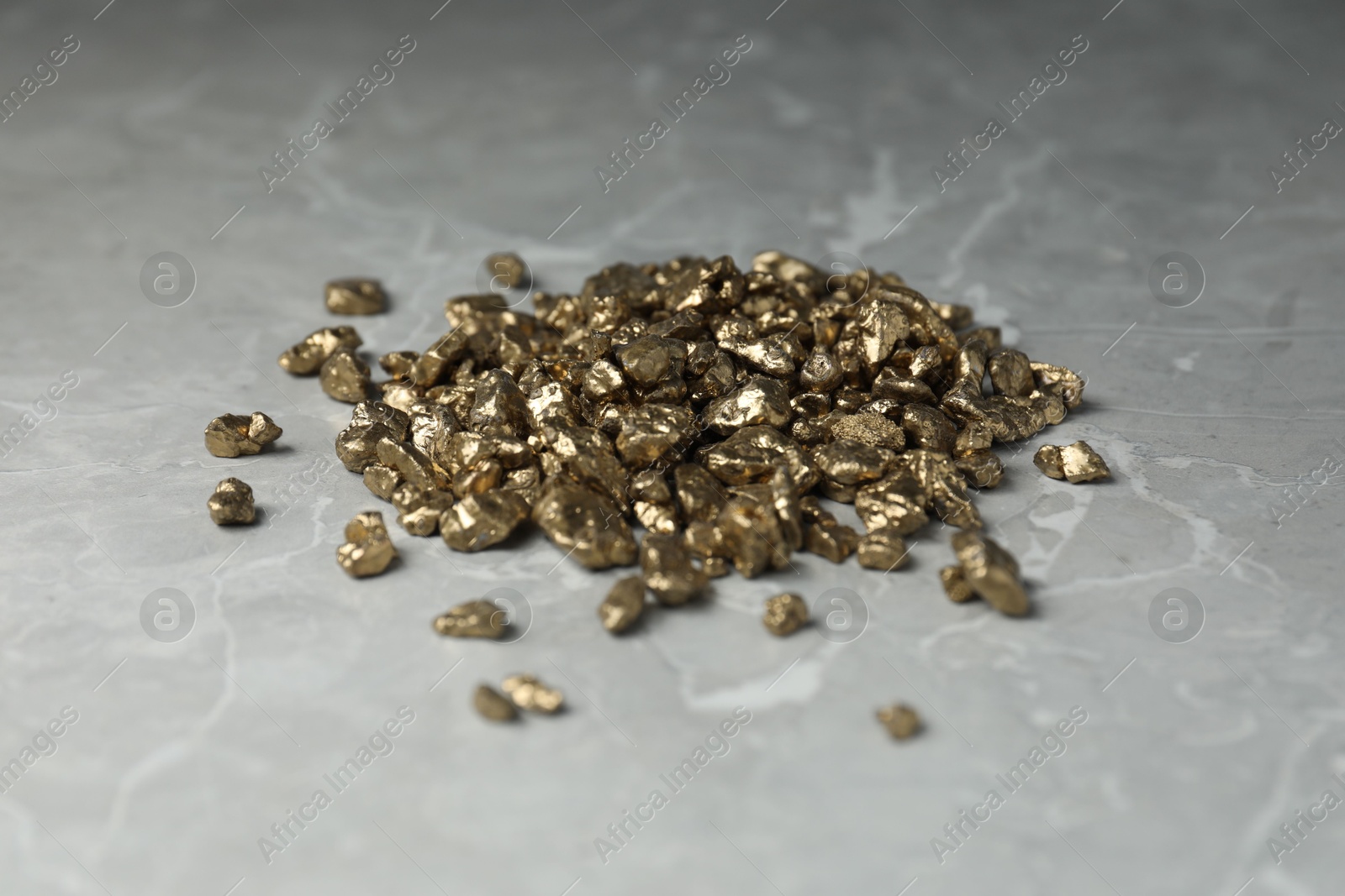 Photo of Gold nuggets on grey marble table, closeup