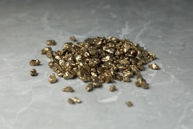 Photo of Gold nuggets on grey marble table, closeup