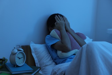 Photo of Afraid girl covering face with hands in bed at night