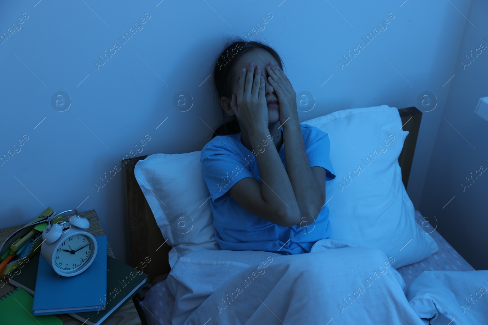 Photo of Afraid girl covering face with hands in bed at night