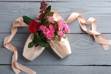 Photo of Pair of beautiful pointe shoes and flowers on grey wooden table, top view