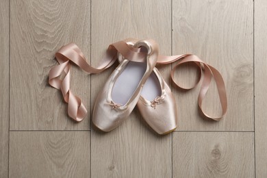 Photo of Pair of beautiful pointe shoes on wooden floor, top view