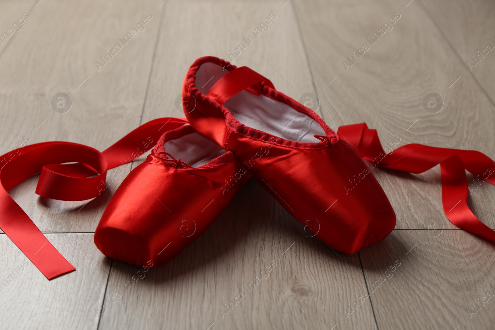 Photo of Pair of red pointe shoes on wooden floor