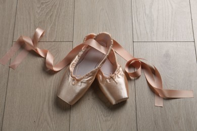 Photo of Pair of beautiful pointe shoes on wooden floor, above view