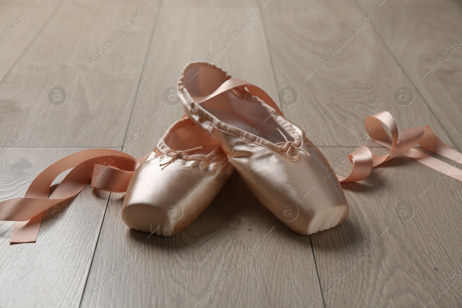 Photo of Pair of beautiful pointe shoes on wooden floor