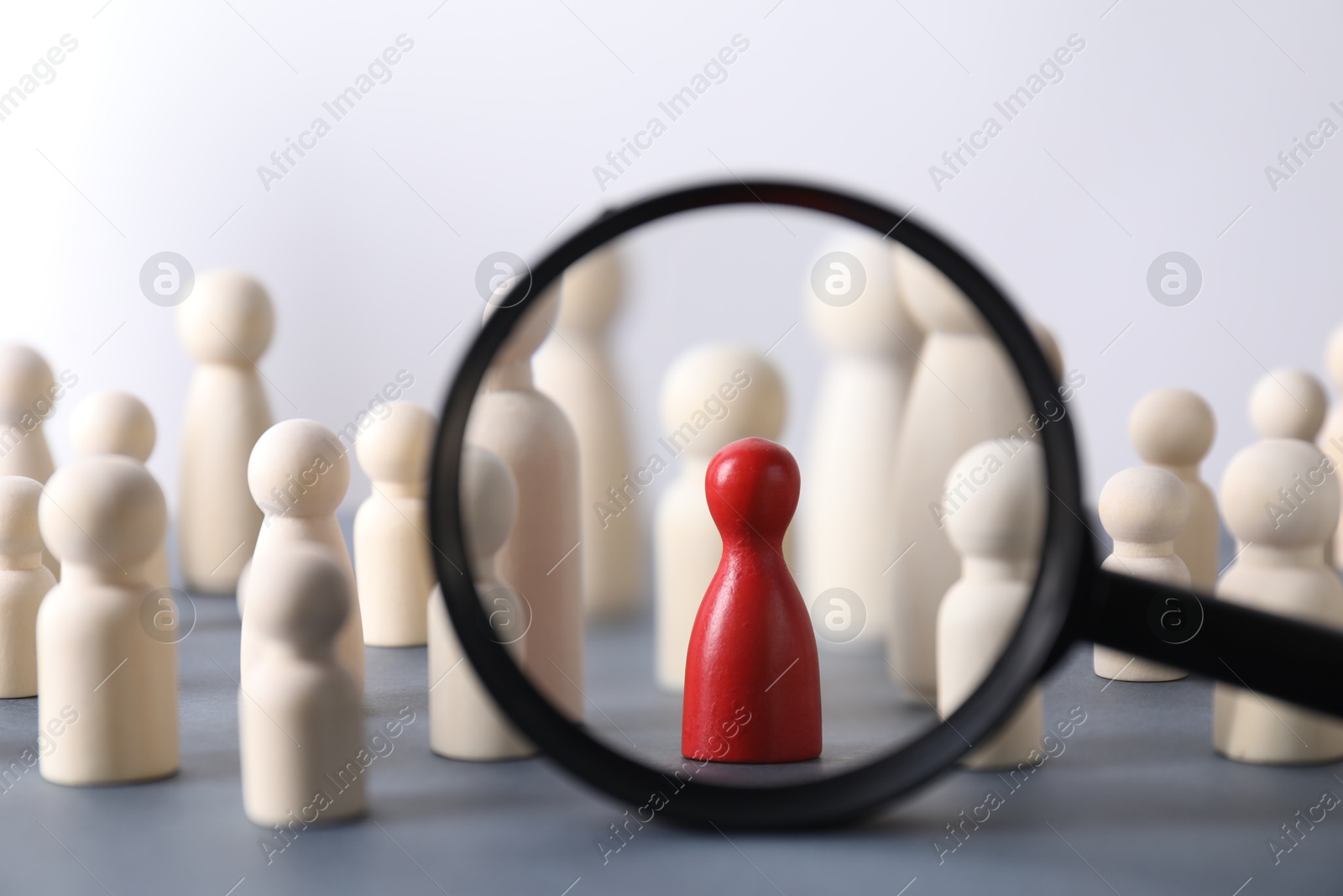 Photo of Human resources concept. Looking at wooden figures through magnifying glass on table against light background, closeup