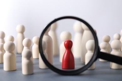 Photo of Human resources concept. Looking at wooden figures through magnifying glass on table against light background, closeup