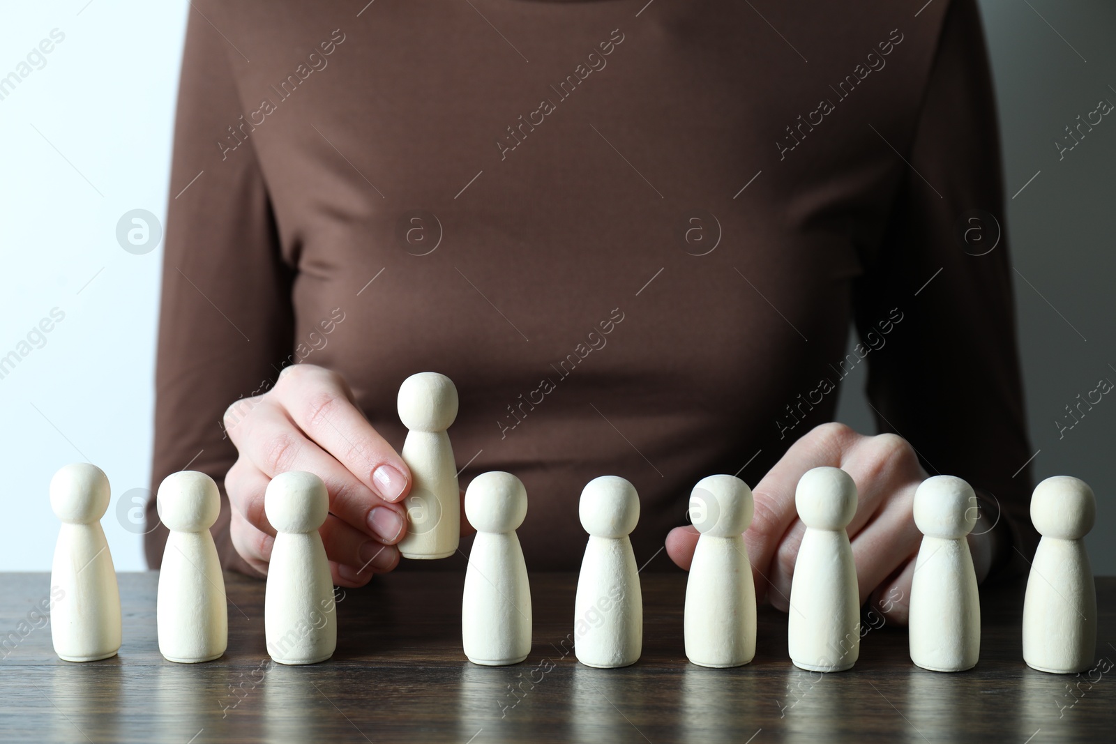 Photo of Human resources concept. Woman choosing wooden piece between other ones at table, closeup