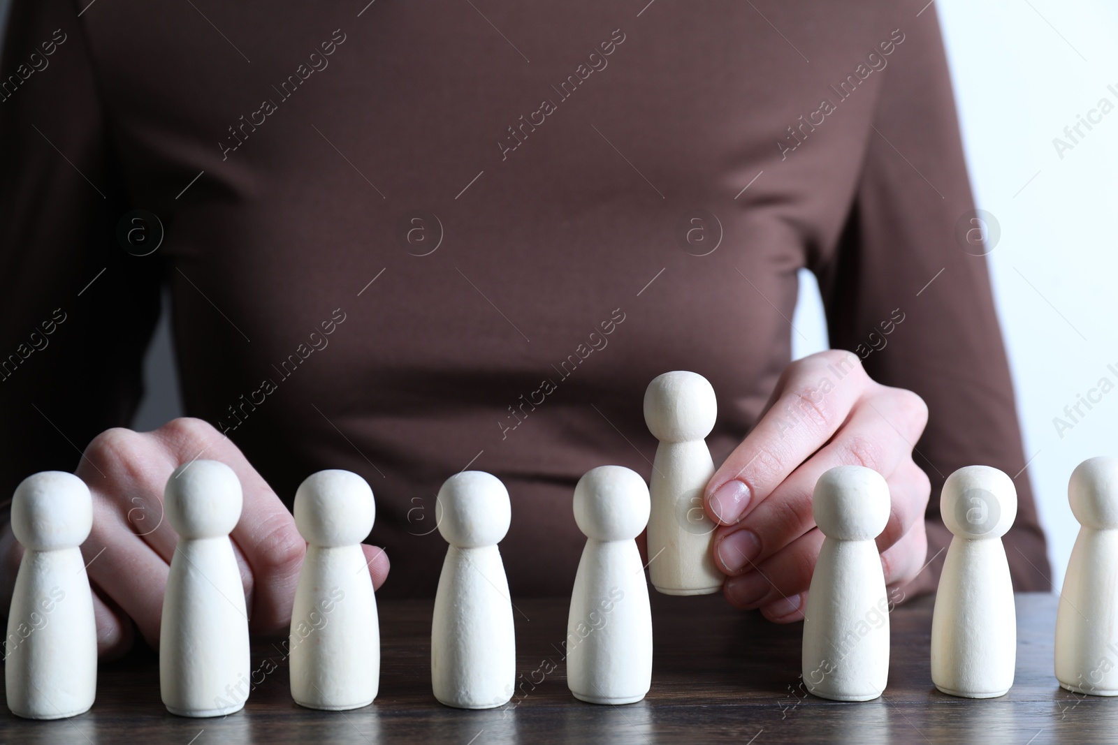 Photo of Human resources concept. Woman choosing wooden piece between other ones at table, closeup