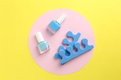 Photo of Pedicure procedure. Nail polishes in bottles and toe separators on color background, flat lay