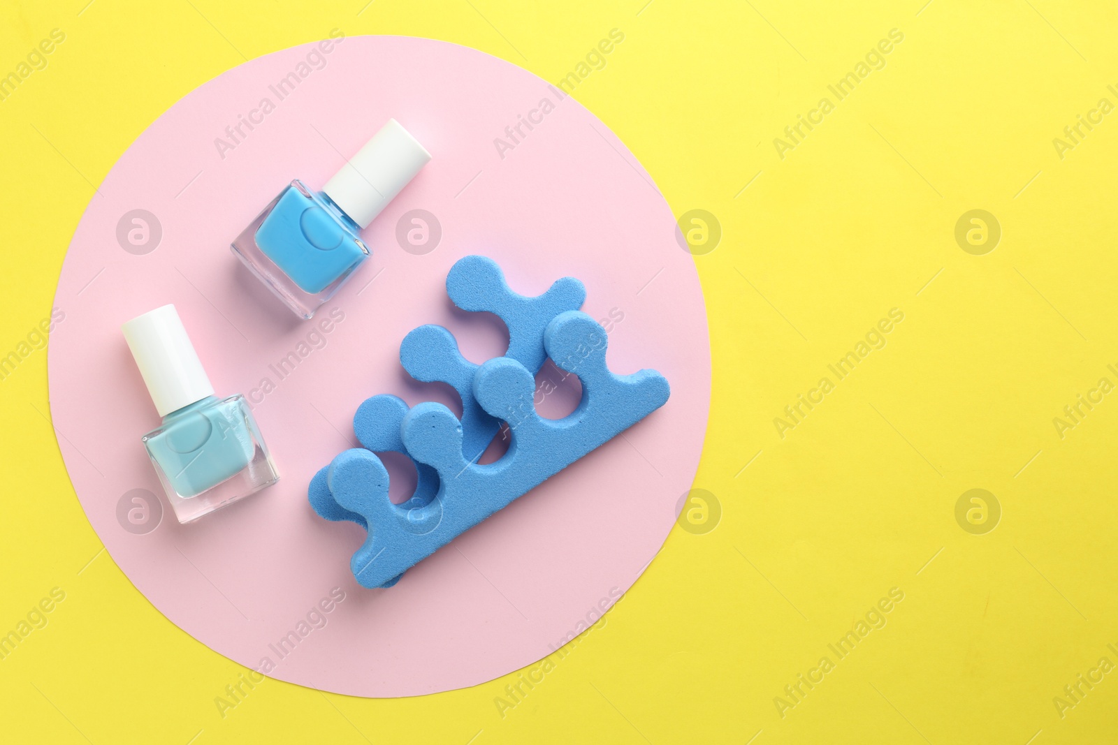 Photo of Pedicure procedure. Nail polishes in bottles and toe separators on color background, flat lay. Space for text