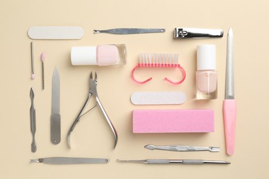 Photo of Set of pedicure tools on beige background, flat lay