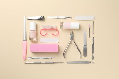 Photo of Set of pedicure tools on beige background, flat lay