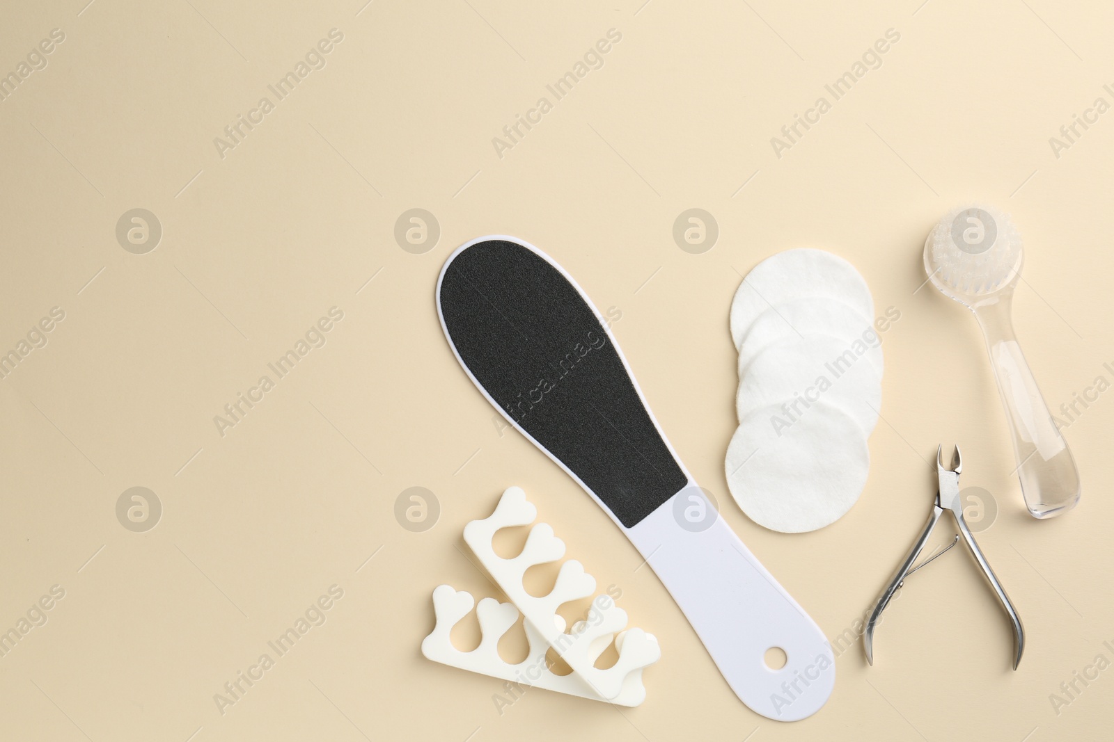 Photo of Set of pedicure tools on beige background, flat lay. Space for text