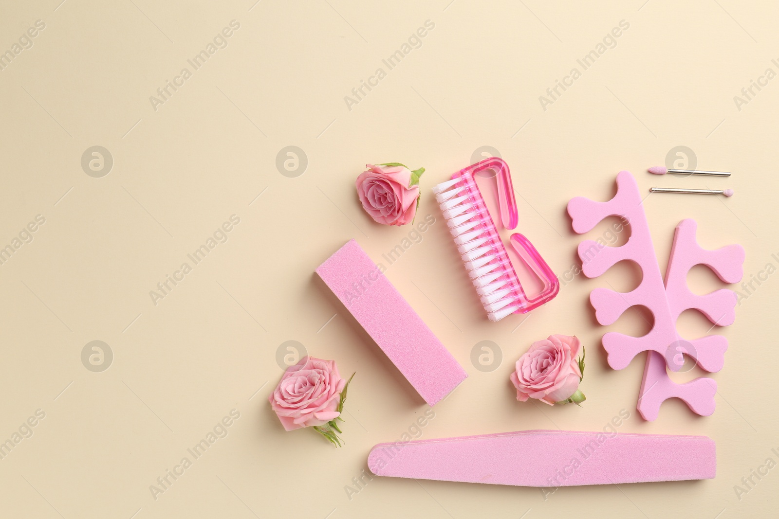 Photo of Set of pedicure tools and flowers on beige background, flat lay. Space for text