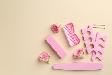 Photo of Set of pedicure tools and flowers on beige background, flat lay. Space for text