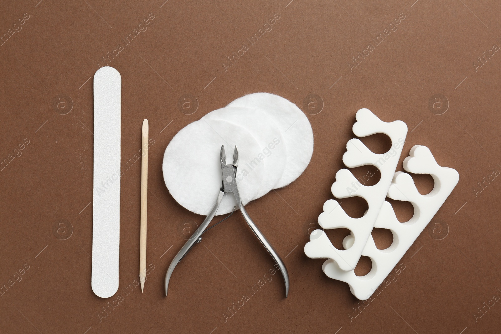 Photo of Set of pedicure tools on brown background, flat lay