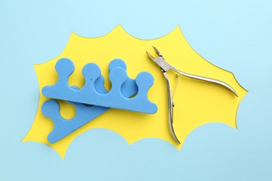 Photo of Pedicure procedure. Nippers and toe separators on color background, flat lay