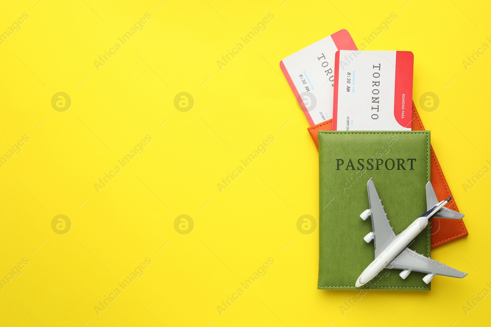 Photo of Travel agency. Flight tickets, passports and plane model on yellow background, top view. Space for text