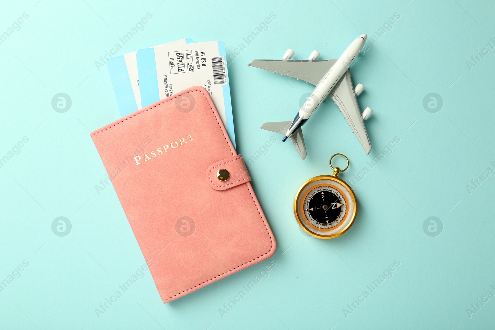 Photo of Passport with tickets, plane model and compass on light blue background, flat lay