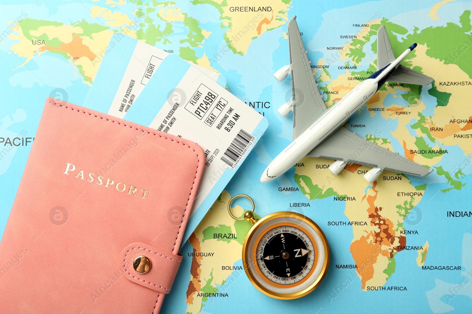 Photo of Passport with tickets, compass and plane model on world map, flat lay