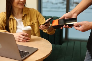 Photo of Woman paying with smartphone via terminal in cafe, closeup