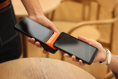 Photo of Woman paying with smartphone via terminal in cafe, closeup