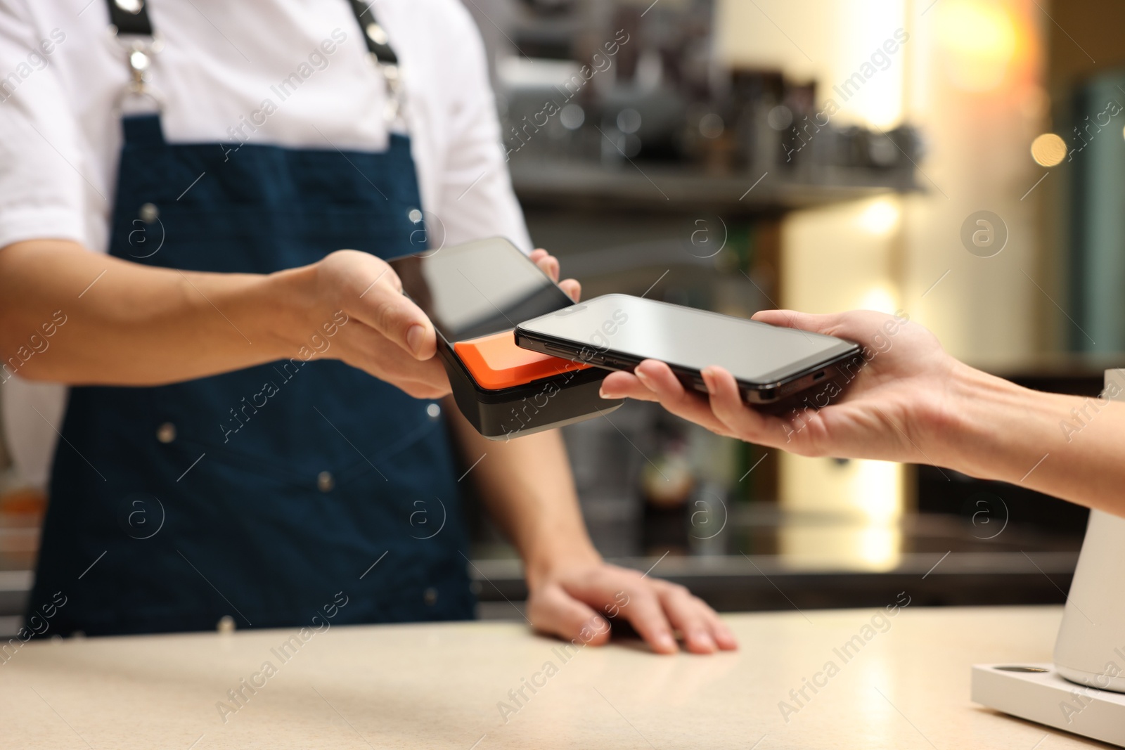 Photo of Woman paying with smartphone via terminal in cafe, closeup