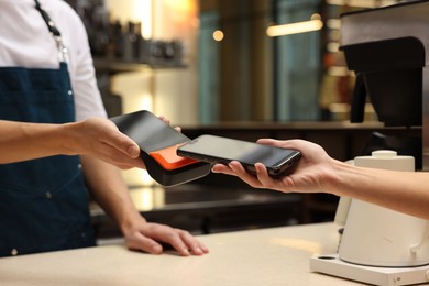 Photo of Woman paying with smartphone via terminal in cafe, closeup