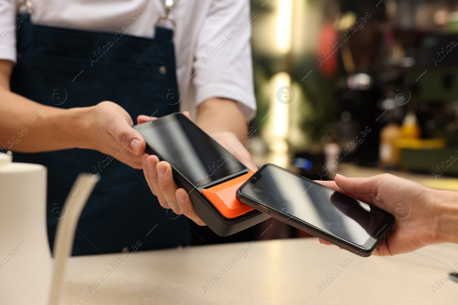 Photo of Woman paying with smartphone via terminal in cafe, closeup