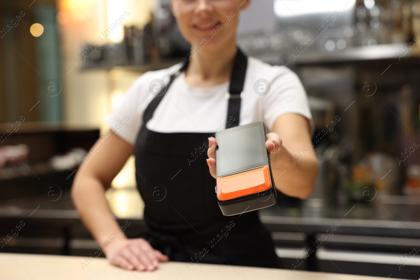 Photo of Cafe worker with payment terminal indoors, closeup