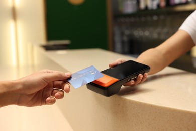 Photo of Man paying with credit card via terminal in cafe, closeup