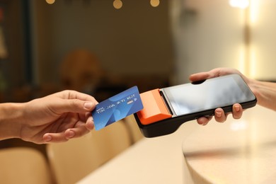 Photo of Man paying with credit card via terminal in cafe, closeup