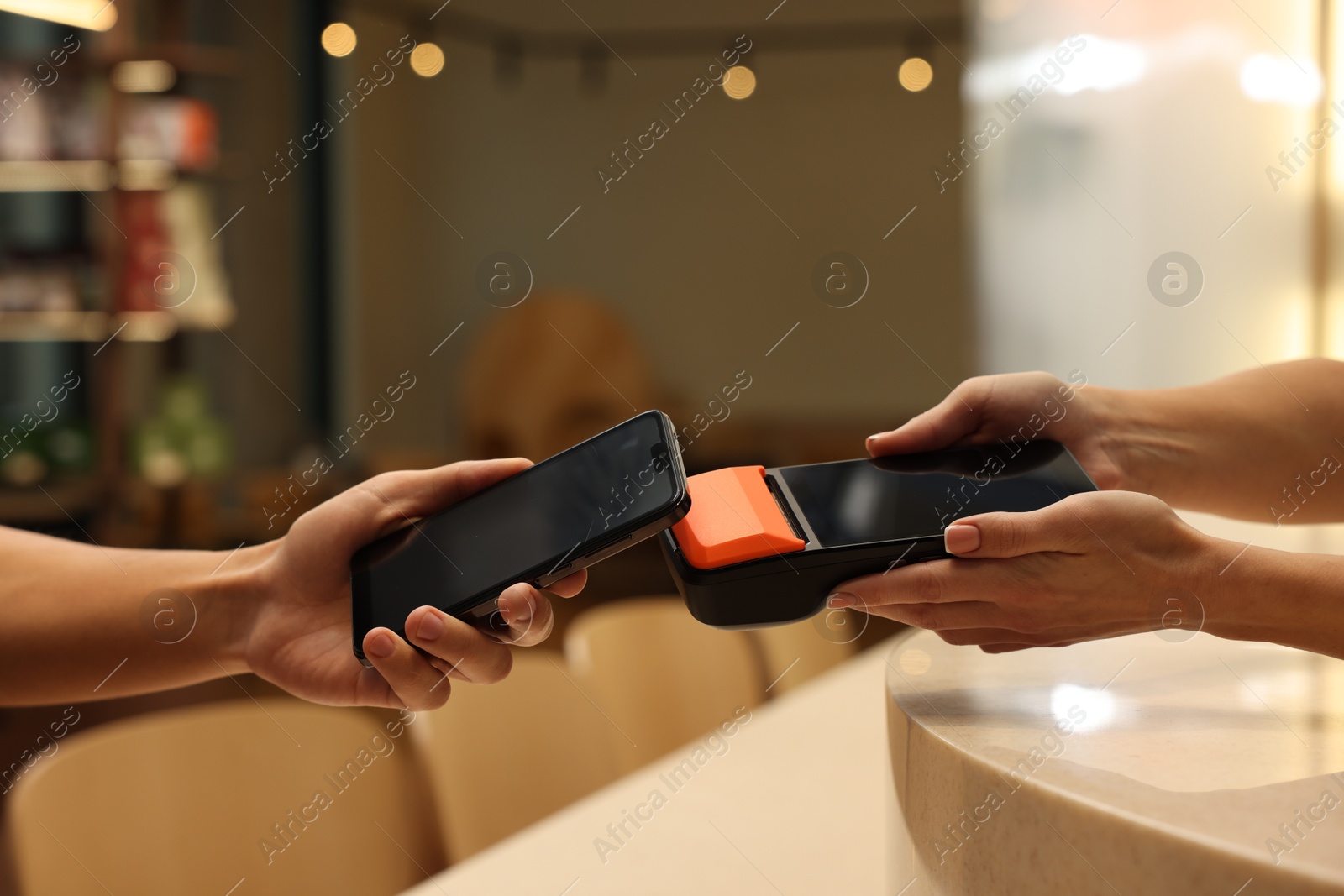 Photo of Man paying with smartphone via terminal in cafe, closeup