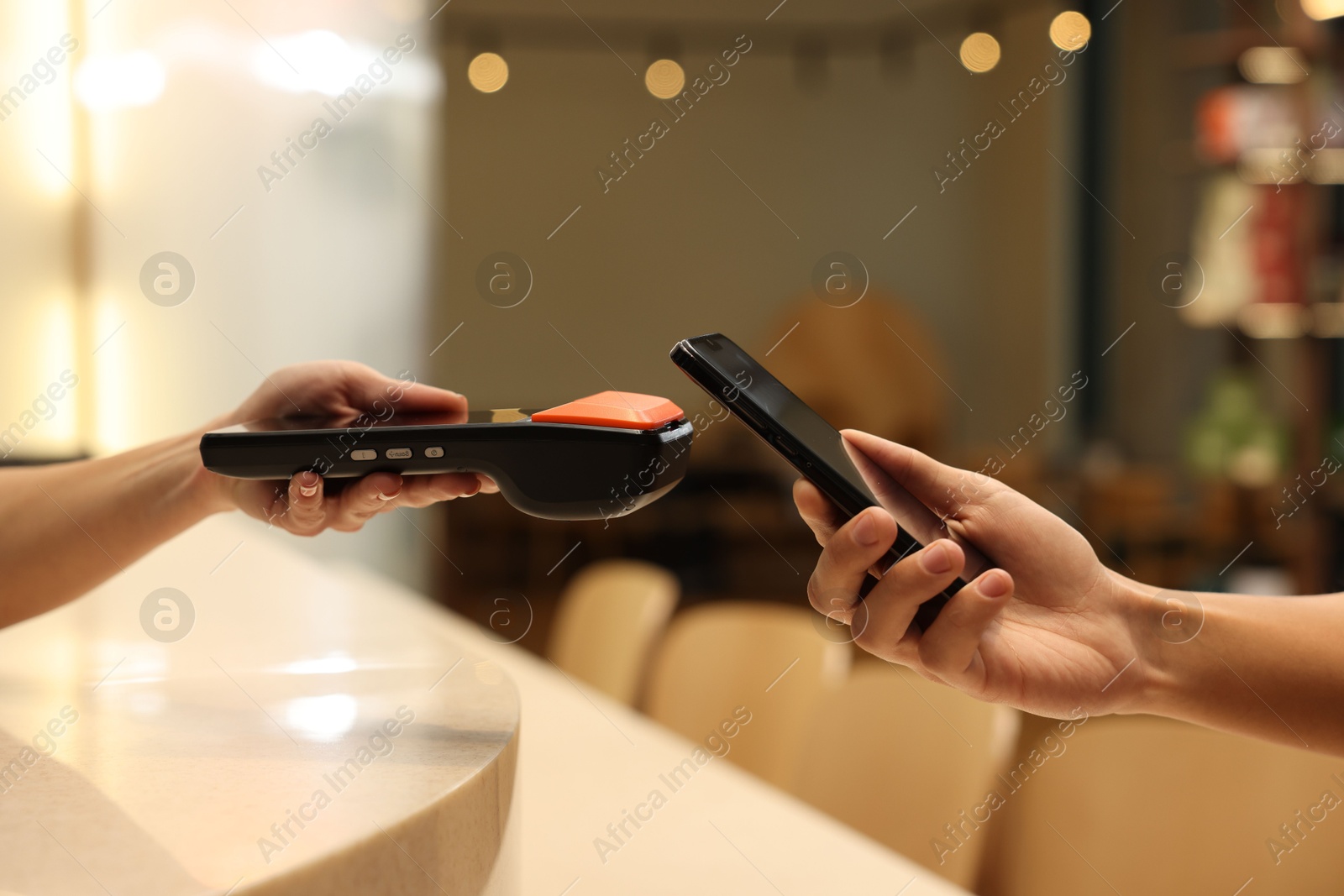 Photo of Man paying with smartphone via terminal in cafe, closeup