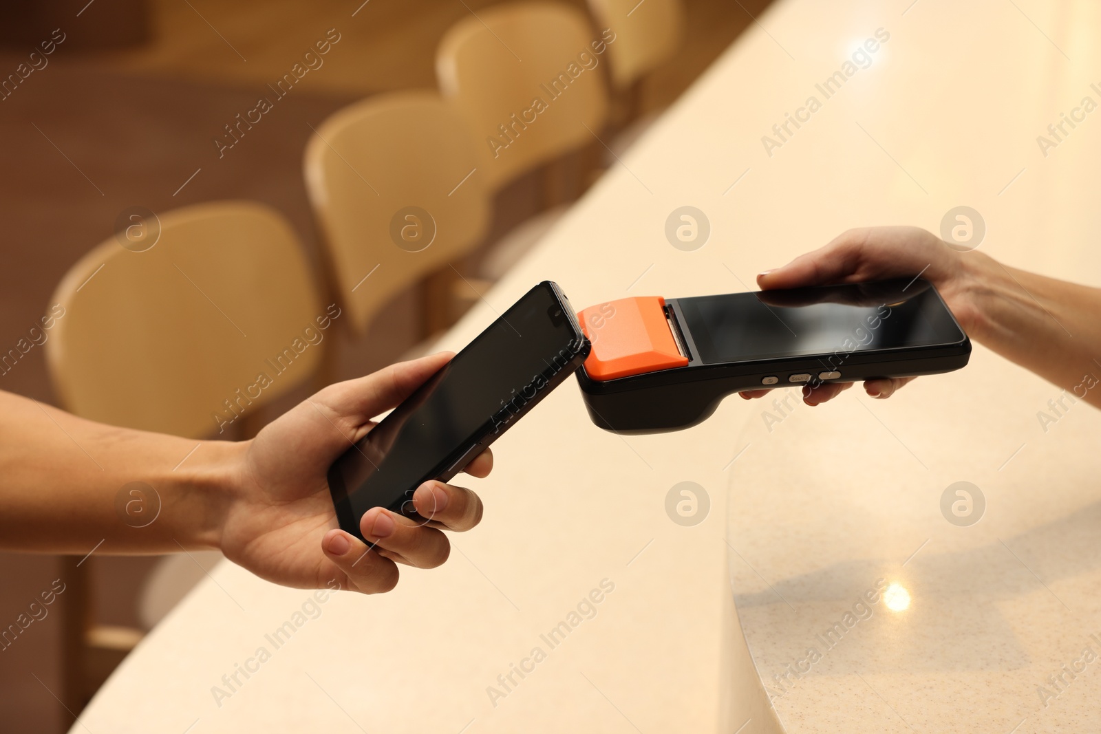 Photo of Man paying with smartphone via terminal in cafe, closeup