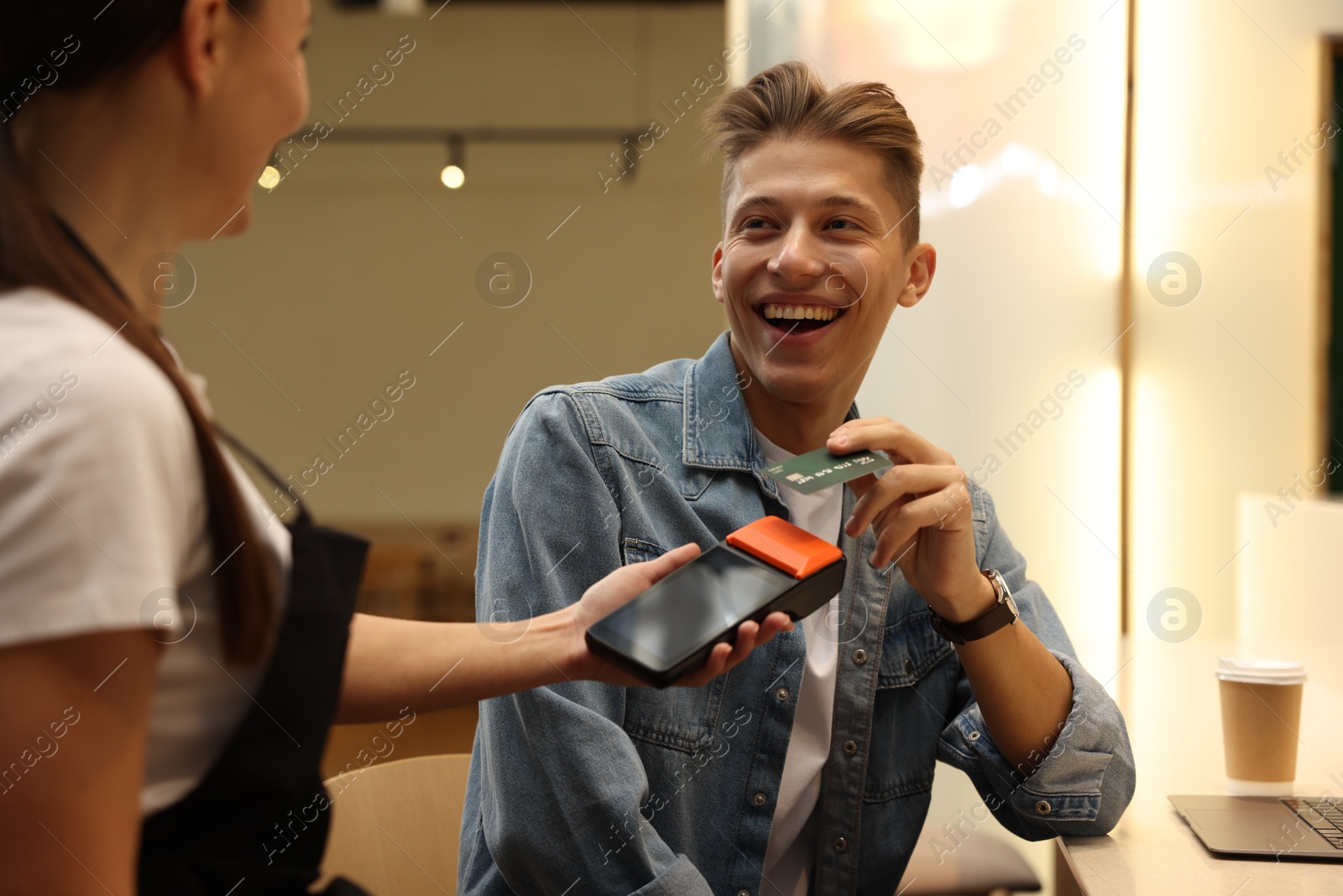 Photo of Man paying with credit card via terminal in cafe