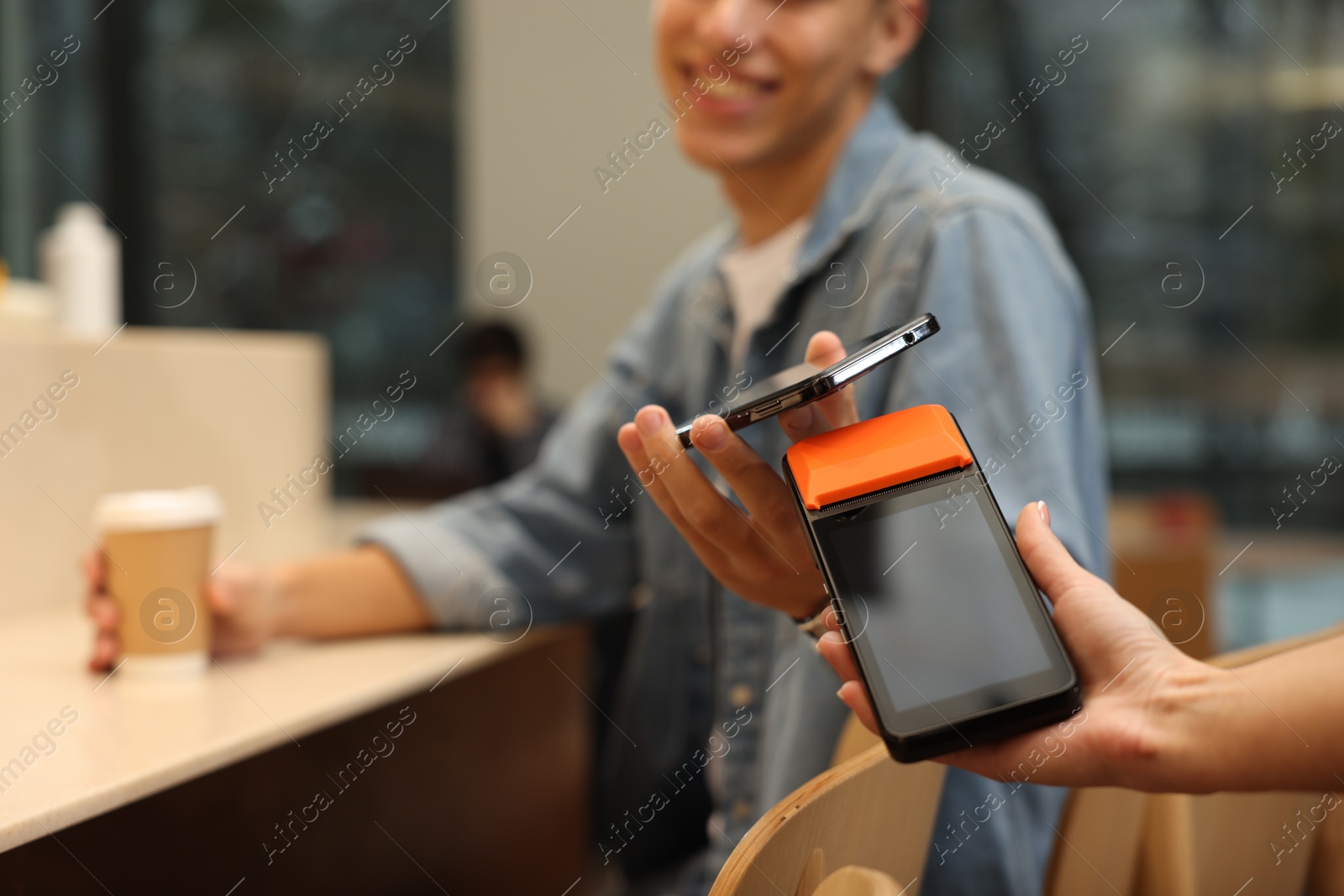 Photo of Man paying with smartphone via terminal in cafe, closeup